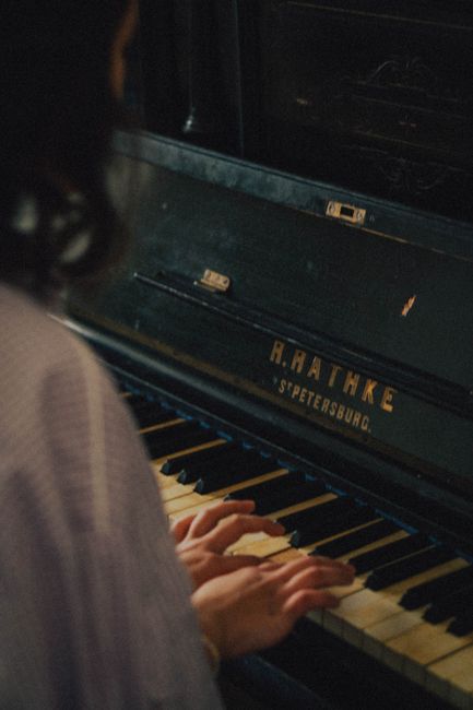 A person playing a vintage R. Rathke piano, focusing on the hands and keys.