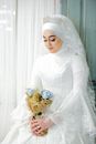 Woman in White Long Sleeve Dress Holding Bouquet of Flowers
