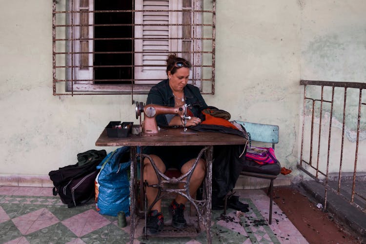 Woman Sitting By A Table And Sewing