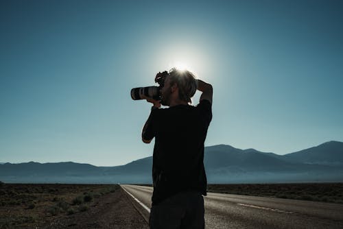 Free Photo of a Man Using His Camera Near a Road Stock Photo