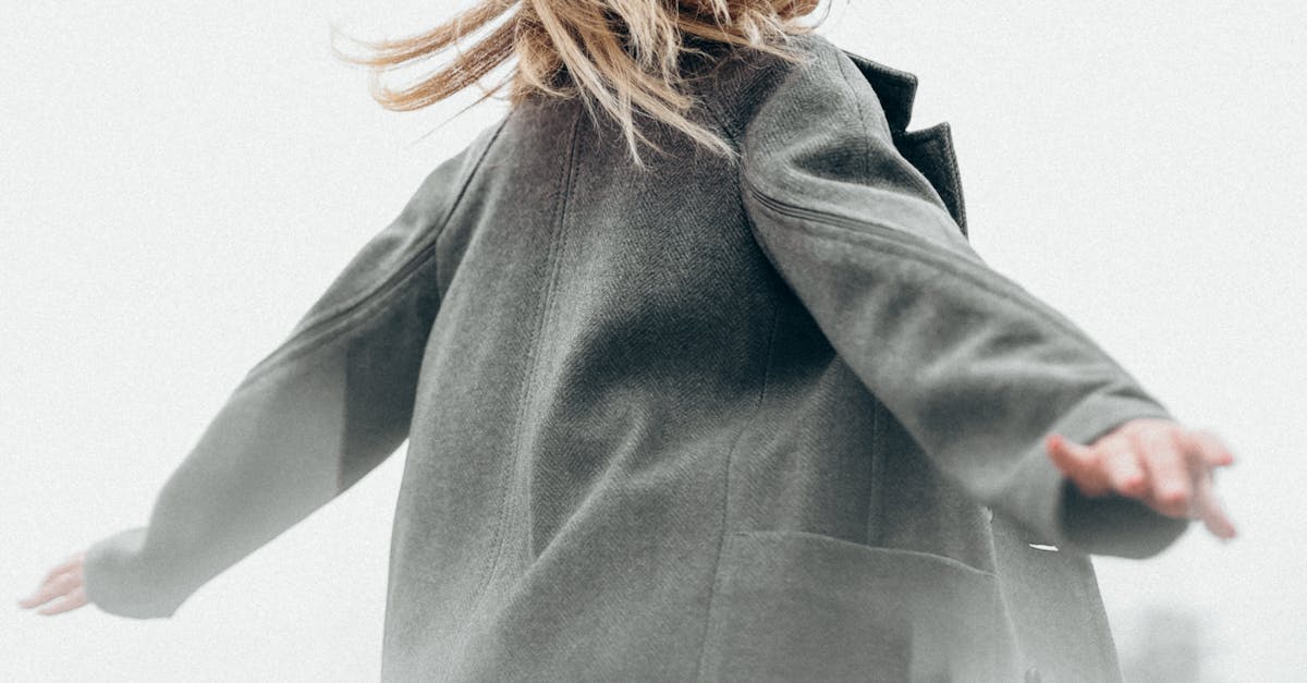 A woman enjoys the freedom of an open field with arms outstretched and hair blown by the wind.
