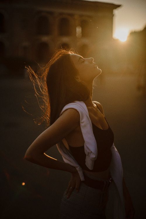 Free A woman enjoys the golden sunset with her head tilted back in Kyiv, Ukraine. Stock Photo