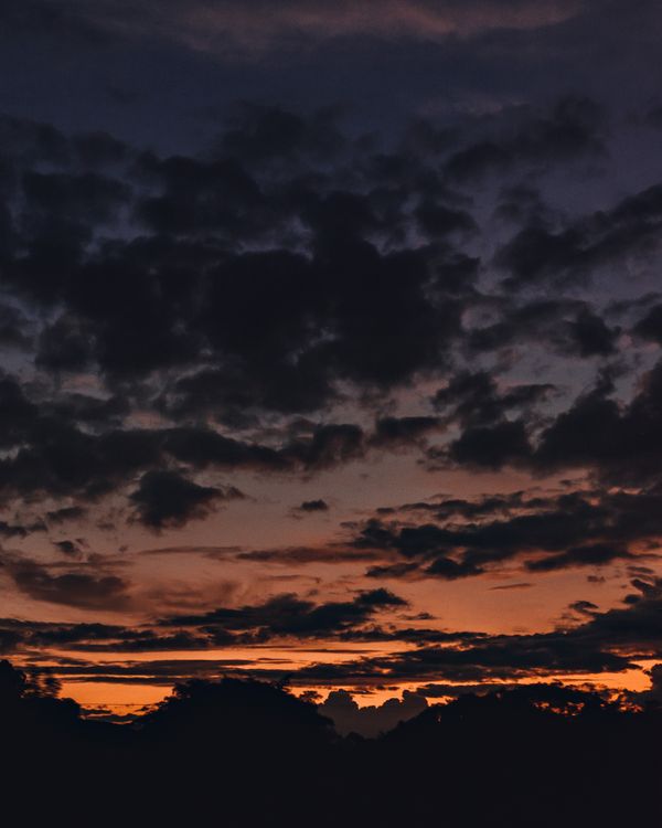 Capture a beleza de uma silhueta escura contra um céu crepuscular dramático com nuvens vibrantes.