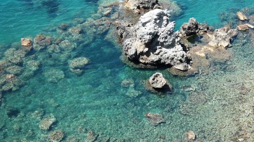 Free Stunning aerial view of a rocky coastline with clear turquoise waters and visible rock formations. Stock Photo