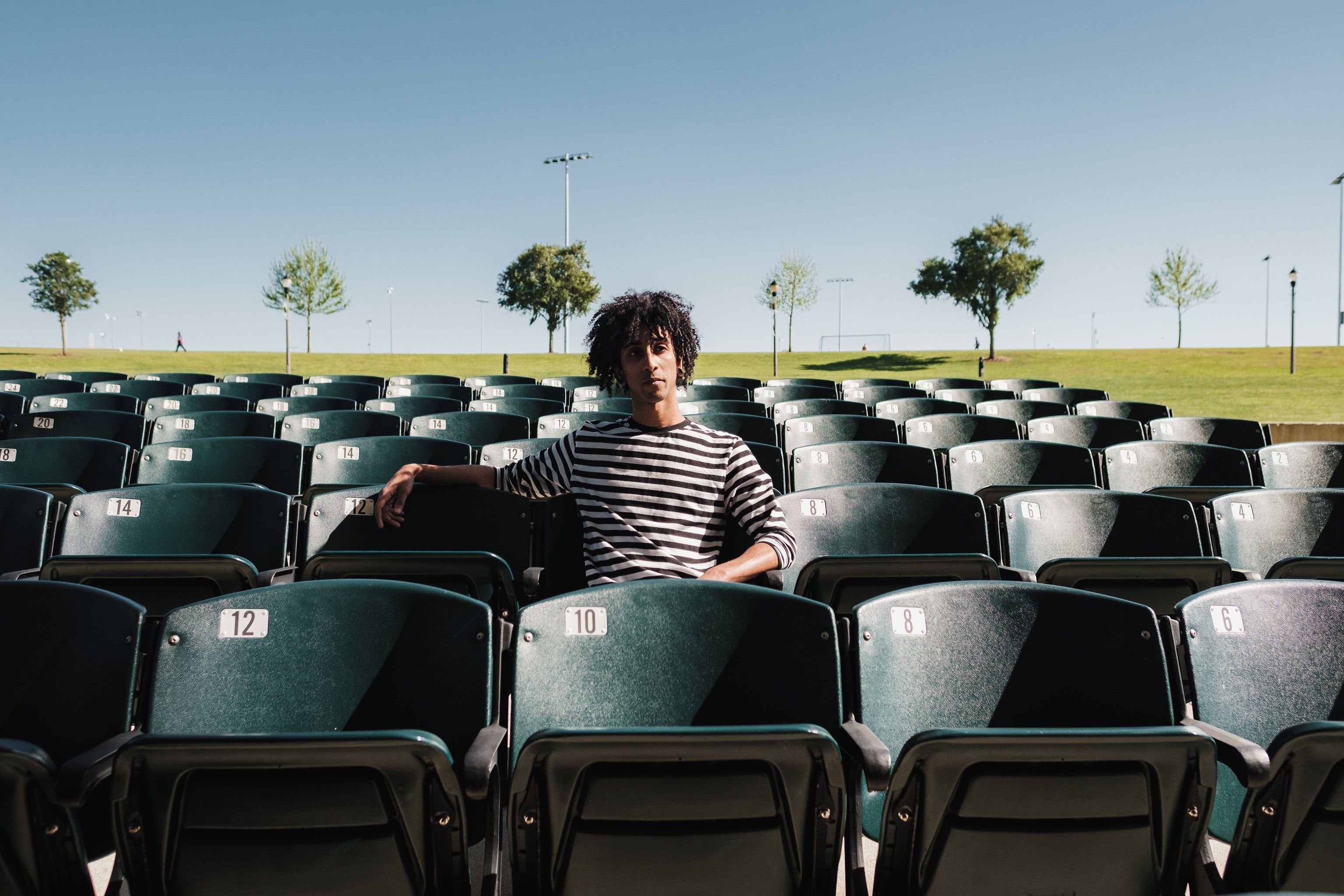 A lone athlete sitting on a bench, head down, with an empty stadium behind them