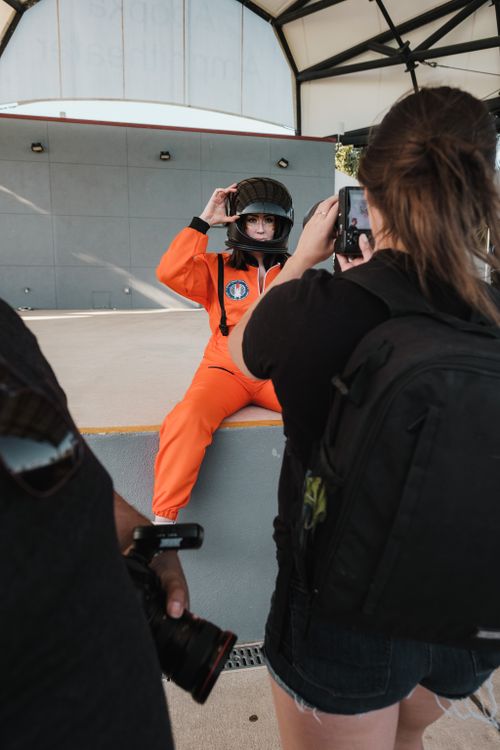 Free Model in orange spacesuit posing for a photo during an outdoor photoshoot. Stock Photo
