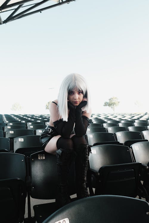 Photo of a Woman in a Costume Sitting on Bleacher Chairs