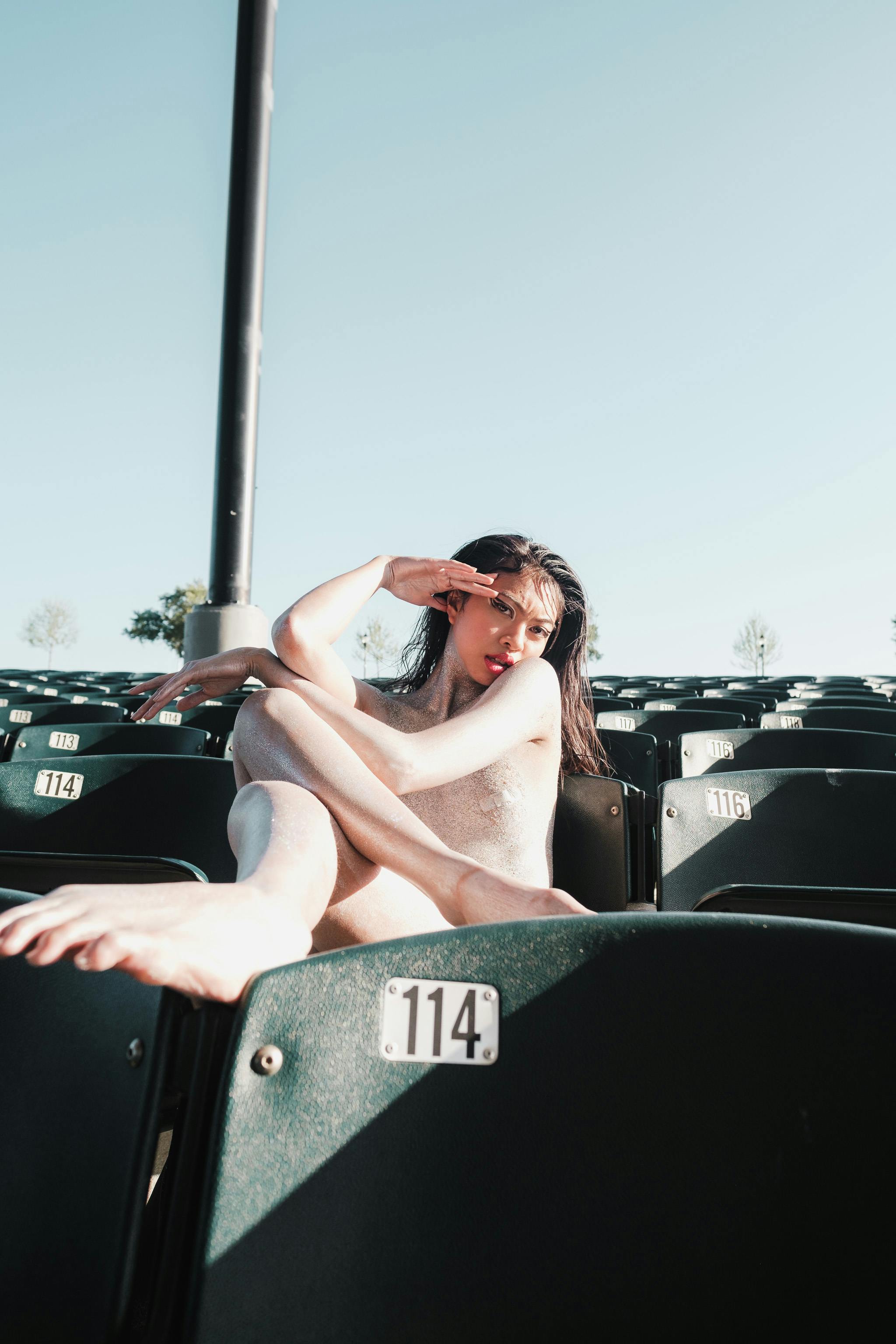 naked woman sitting on stadium seat