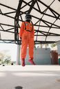 Man in Orange Jacket and Pants Standing on White Floor