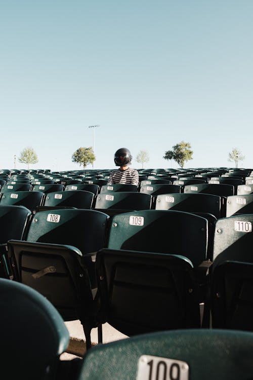 Person in Striped Shirt Sitting on Vacant Row Seats