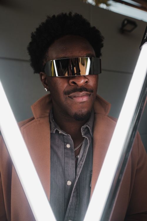 Free Portrait of a fashionable man wearing futuristic sunglasses surrounded by bright lights. Stock Photo