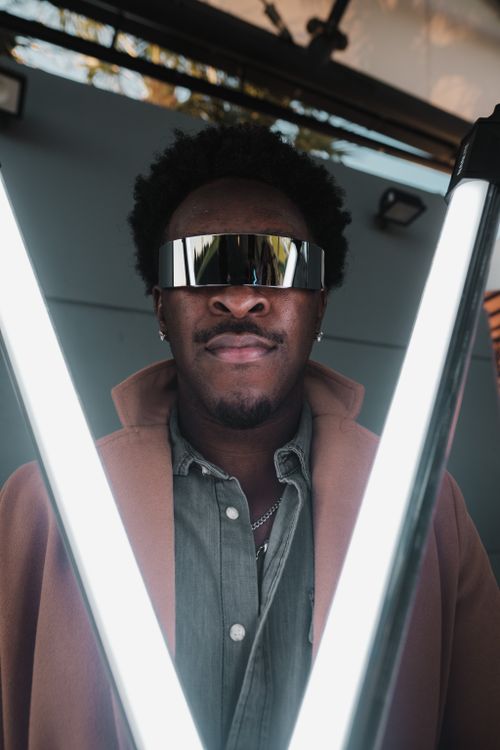 Free Stylish portrait of a man wearing futuristic sunglasses and a coat, illuminated by LED lights. Stock Photo