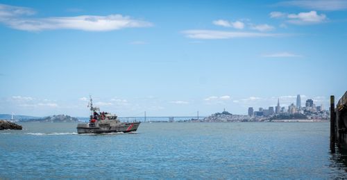 Free Coast Guard ship cruising on San Francisco Bay with skyline and bridges in the background. Stock Photo