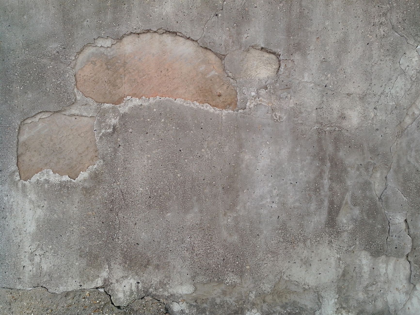 Close-up of a weathered concrete wall with grunge texture and exposed patches.