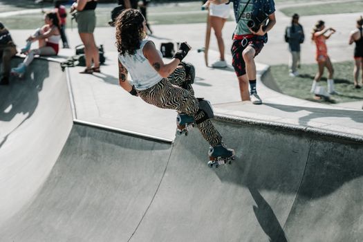 Woman roller skating on ramp at outdoor skatepark. Energetic and lively atmosphere.