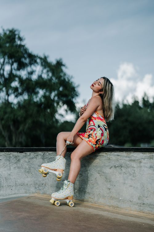 Free A fashionable woman wearing roller skates poses outdoors, showcasing vibrant summer style. Stock Photo