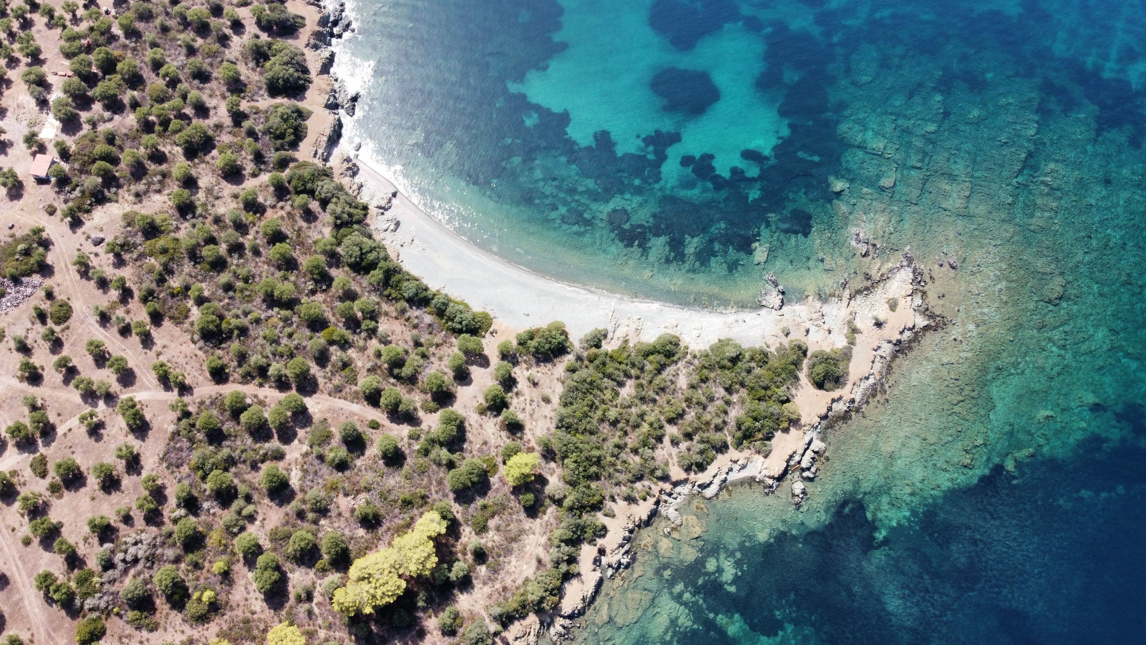 A stunning aerial shot of a Greek coastline with clear blue waters and lush greenery. - Photo by Thanos Skoufitsas on Pexels