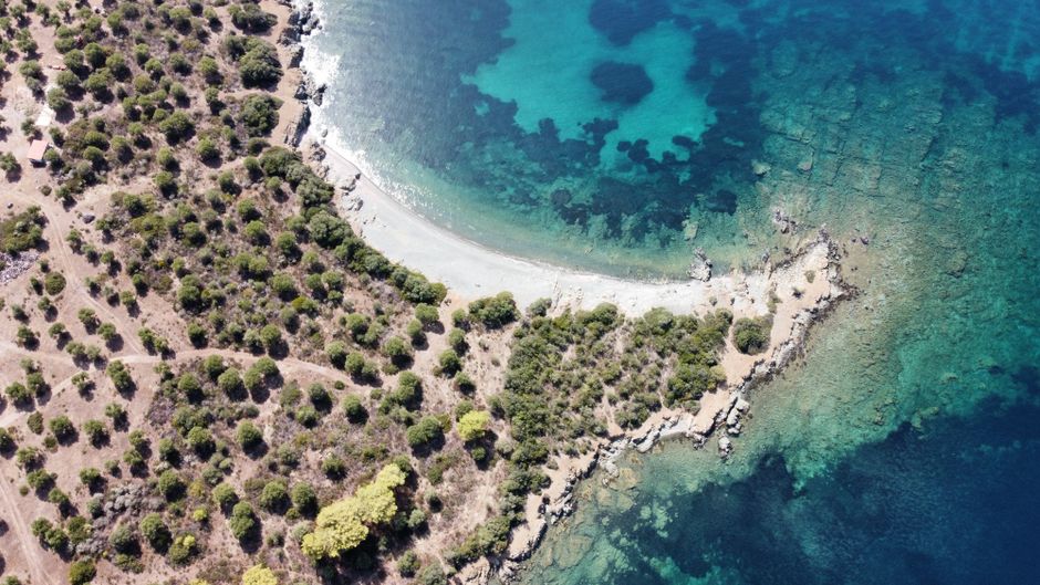 Heldere turquoise baai aan een onbebouwde kustlijn in de Egeïsche Zee
