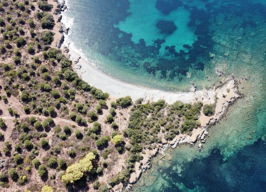 A stunning aerial shot of a Greek coastline with clear blue waters and lush greenery.