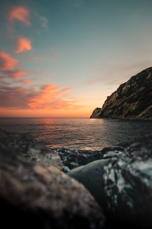 Free Breathtaking view of Liguria's rocky coastline during a vibrant sunset over the sea. Stock Photo