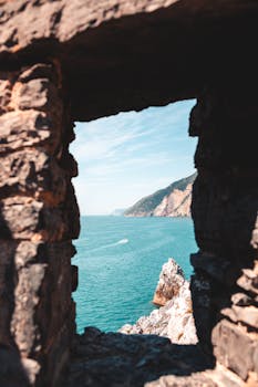 Breathtaking view of Ligurian sea through a stone window, revealing cliffs and blue waters.