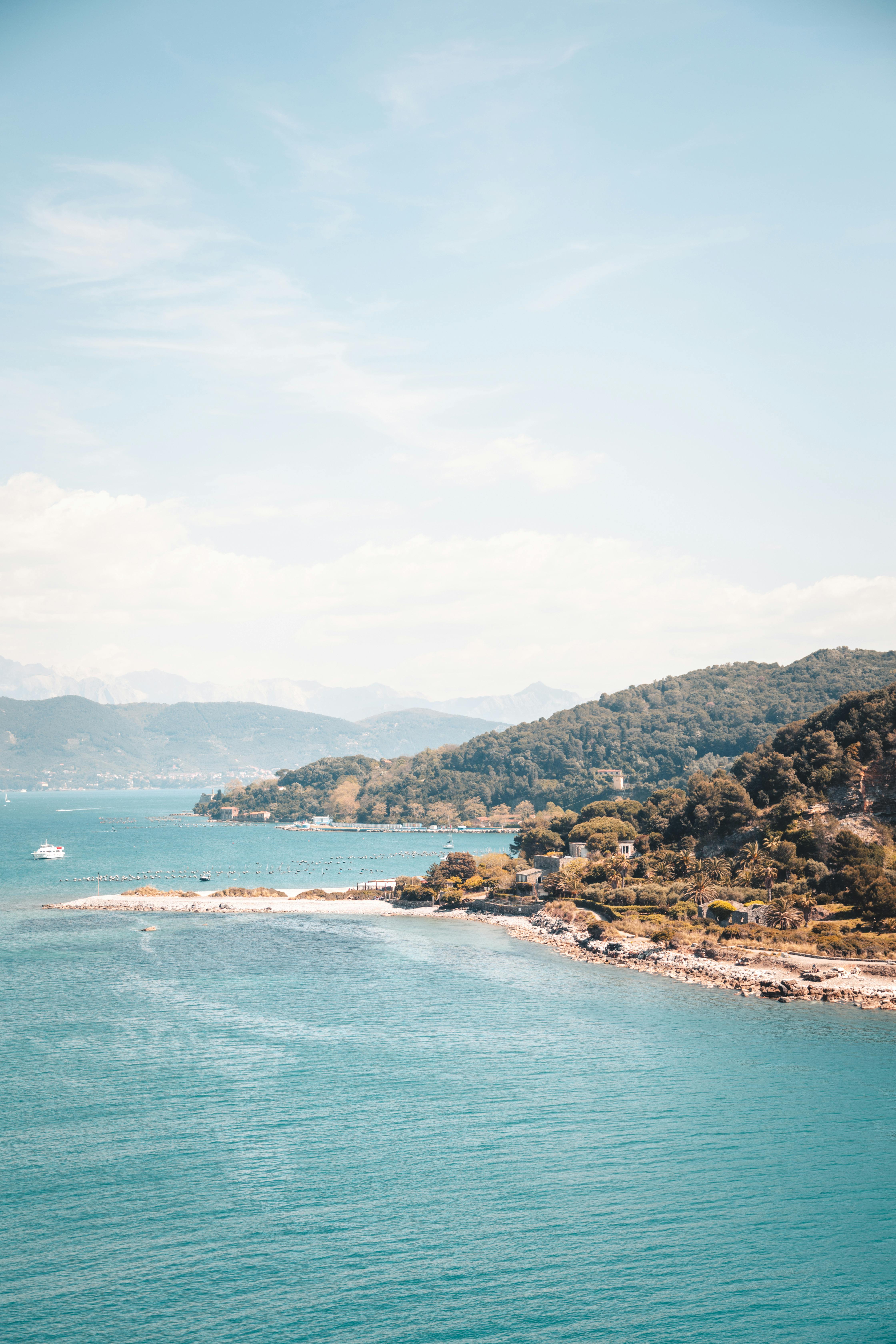 green and brown mountains beside blue sea under blue sky