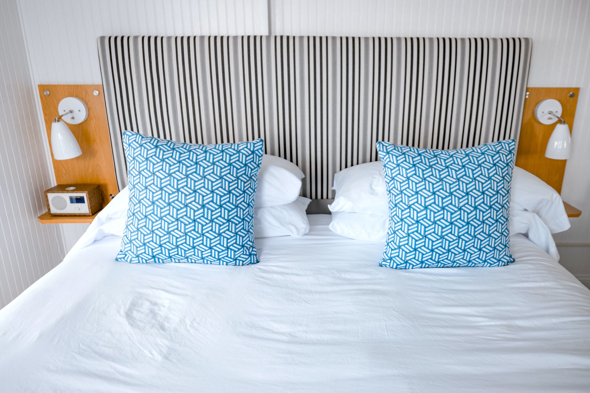 Modern bedroom interior with striped headboard and blue geometric pillows, creating a cozy atmosphere.