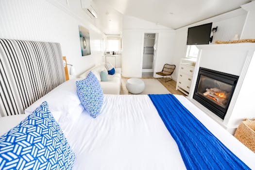 Bright and inviting bedroom with a cozy fireplace and modern decor featuring blue accents.