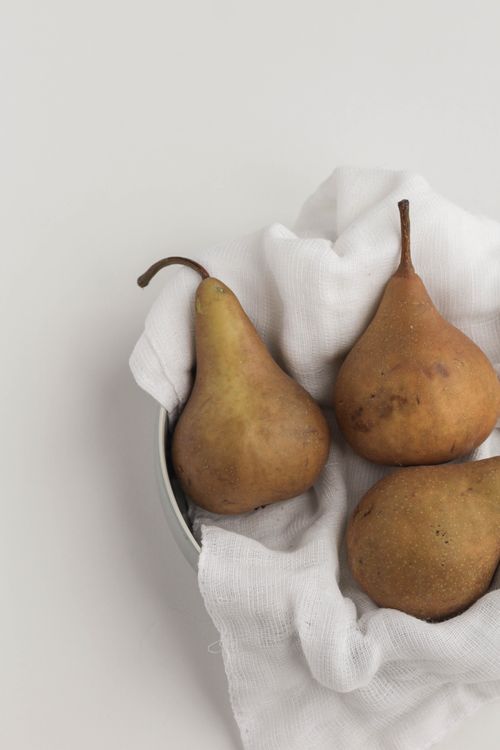 Free Three ripe pears on a white fabric in a bowl, showcasing minimalist and natural aesthetics. Stock Photo