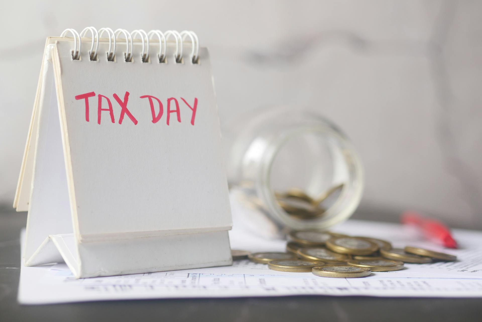 Coins near Block of Notes with Tax Day Text