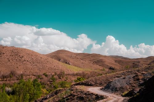 Free Scenic view of rolling mountains beneath a vibrant blue sky and fluffy white clouds. Stock Photo
