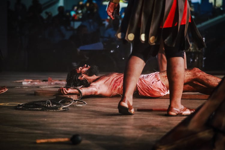 An Actor Portraying Jesus Lying On A Crucifix