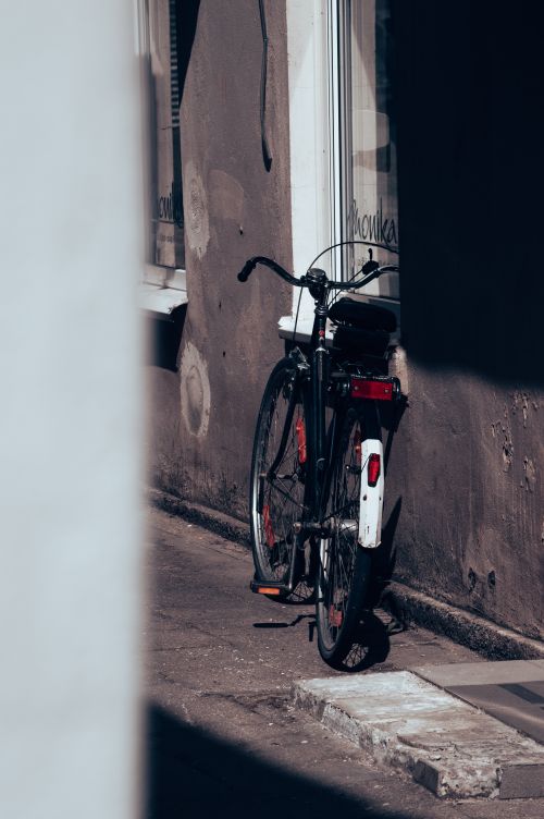 Free A vintage bicycle leaning against a wall in a quaint Lithuanian alleyway, capturing a rustic charm. Stock Photo