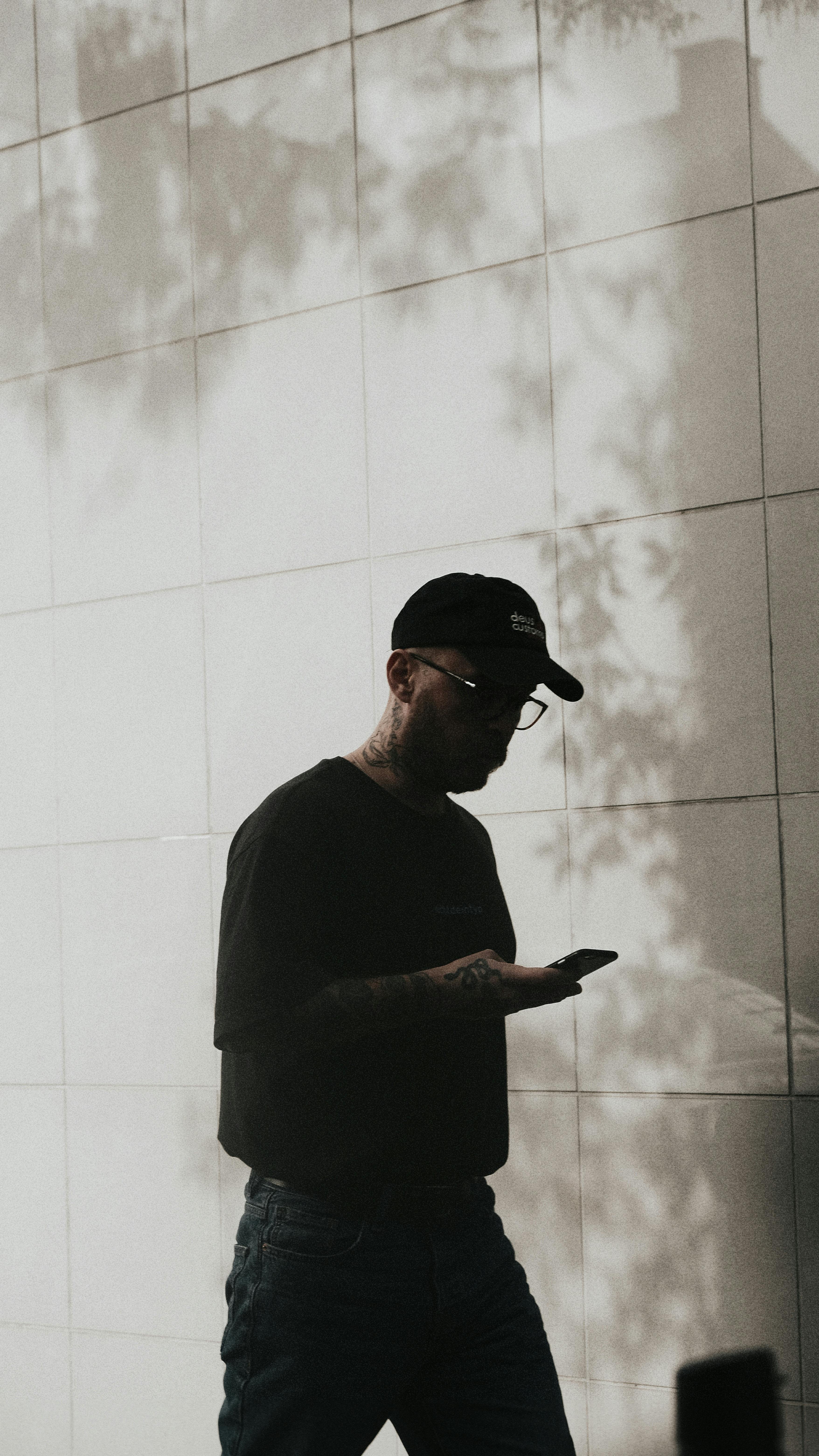 Silhouette of a man walking and using a smartphone with shadows cast on a tiled wall in İstanbul, Turkey.