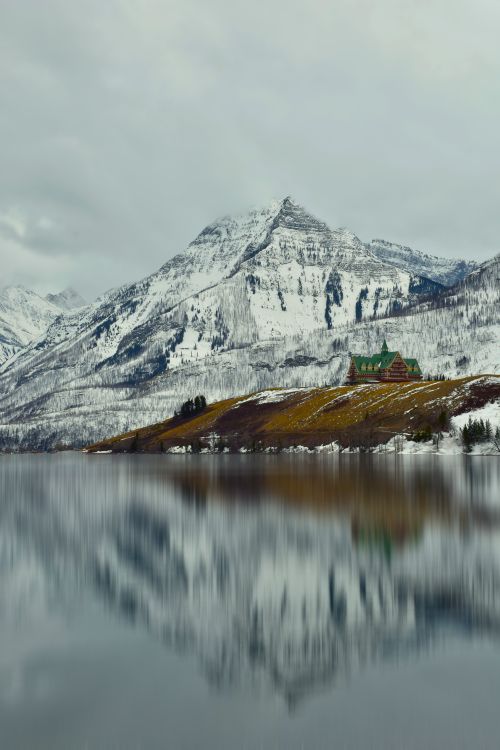 Free A scenic winter landscape with snow-covered mountains and a reflective lake. Stock Photo