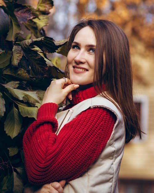 A Woman Wearing a Beige Vest over a Red Knitted Sweater