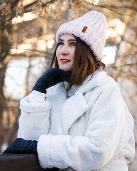 Woman in a white coat and knit hat enjoying a winter day outdoors.
