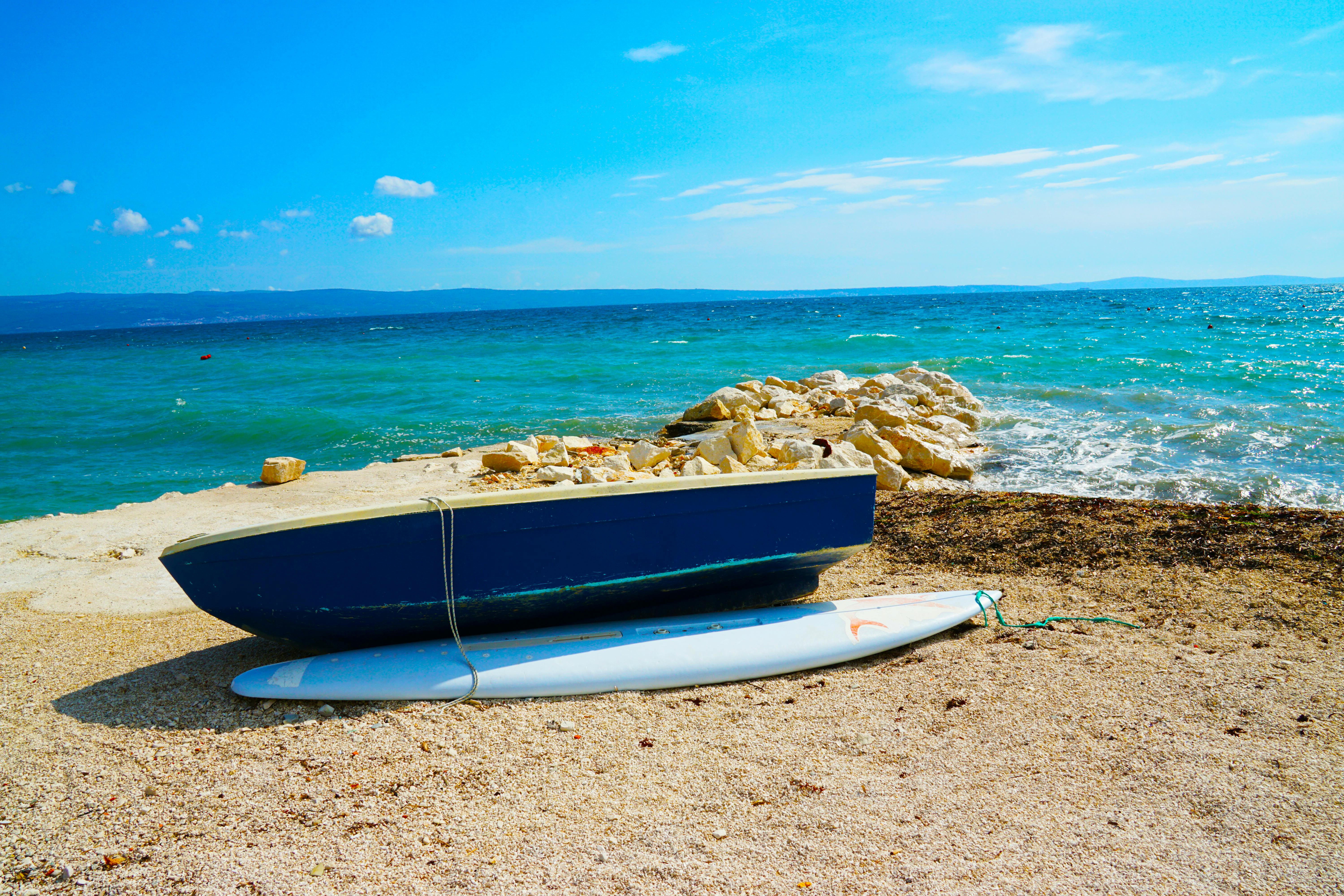 blue wooden dinghy boat beside body of water