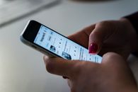 Social media, blog post writing on an iphone, in a woman hand with red nails