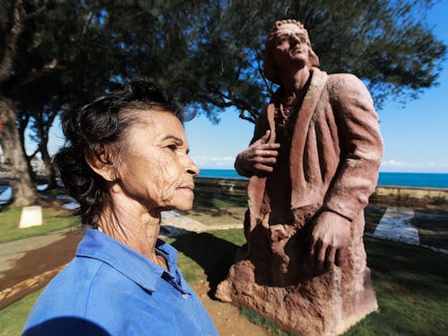 Photo of an Elderly Woman Near a Sculpture