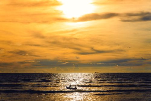 Free A fisherman rows his boat under a golden Cartagena sunset, capturing tranquility and solitude. Stock Photo