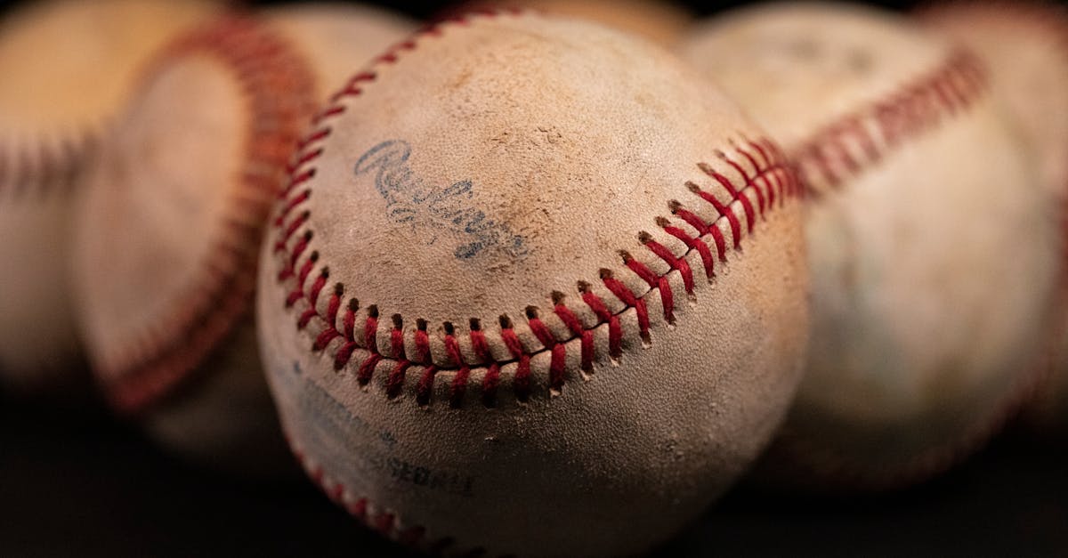 Focused close-up of old baseballs with visible stitching and texture against a dark background.