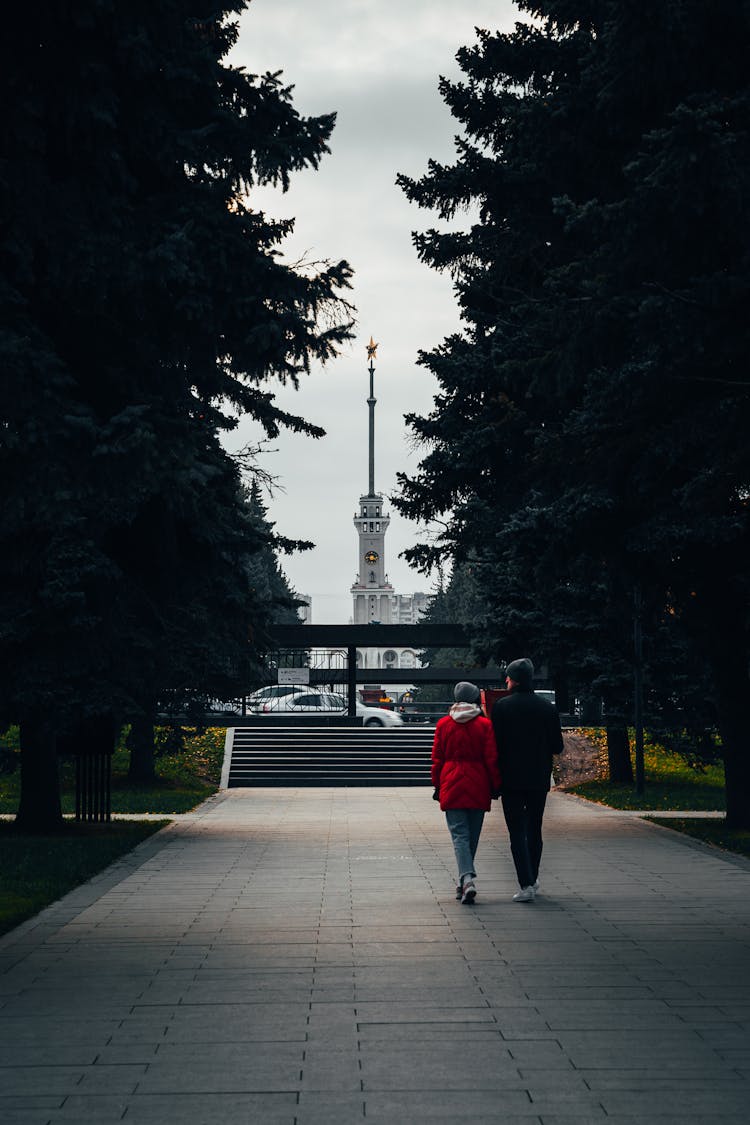 Back View Of A Man And Woman Walking In A Park In City 