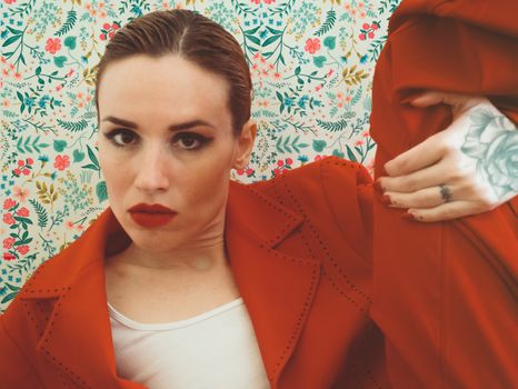 Portrait of a fashionable woman in red against a vibrant floral pattern, exuding style and confidence.