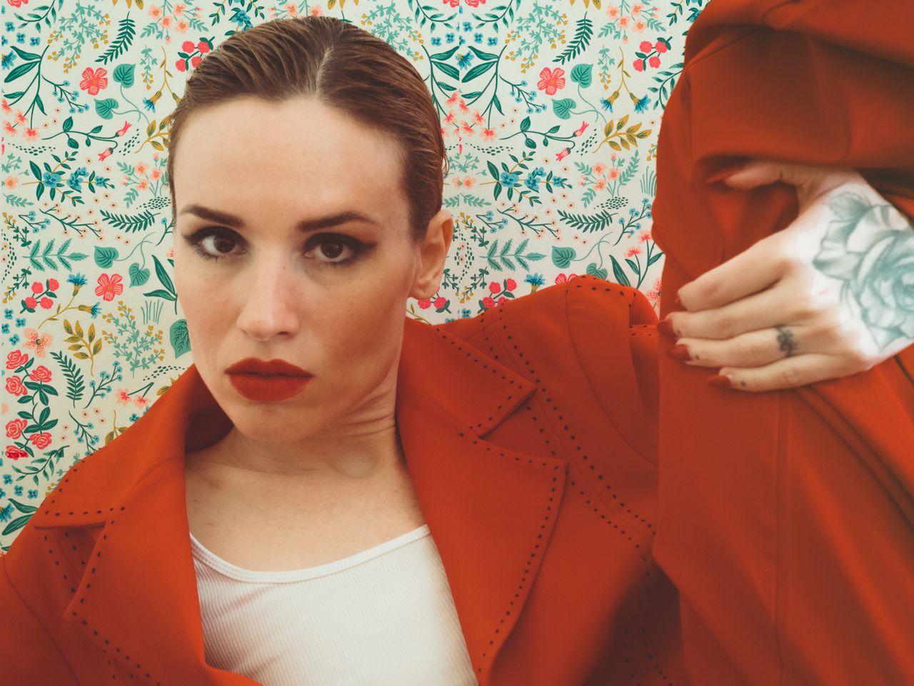 portrait of a fashionable woman in red against a vibrant floral patter