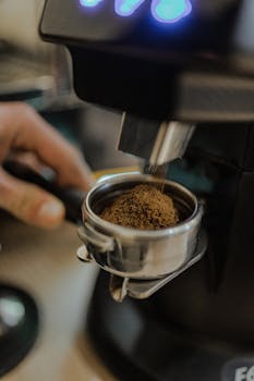 Freshly ground coffee being dispensed into a portafilter for espresso preparation.