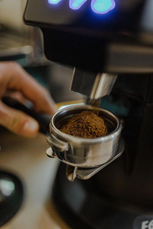 Free Freshly ground coffee being dispensed into a portafilter for espresso preparation. Stock Photo