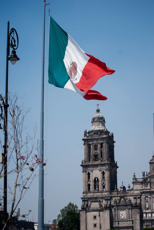 Free Mexican flag waving in front of the historic Metropolitan Cathedral in Mexico City. Stock Photo