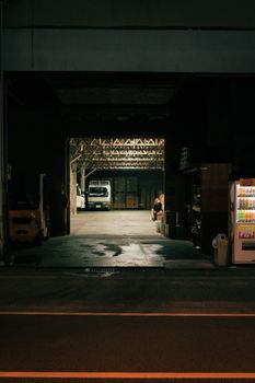 Dimly lit warehouse entrance featuring a vending machine and parked trucks.