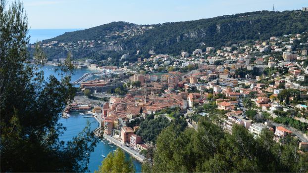Scenic aerial view of a vibrant Mediterranean coastal town with hillside and ocean backdrop.